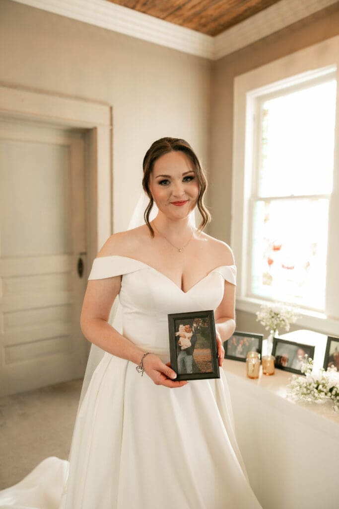 Bride tearing up at the Memorial table at The 1906 wedding venue in Whitesboro, TX