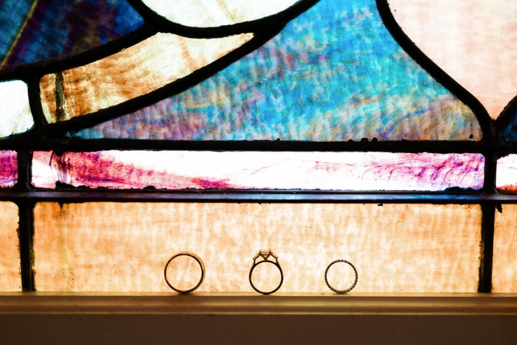 Close-up photo of the wedding rings against stained glass window at The 1906 wedding venue in Whitesboro, TX
