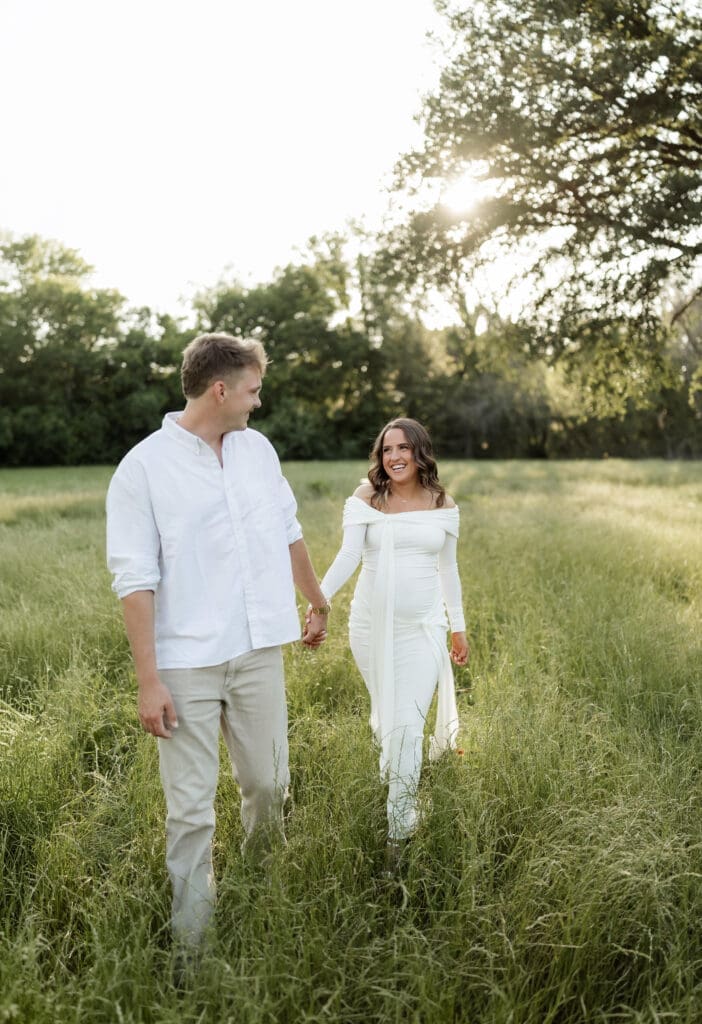 Couple posing in the grassy field during their golden hour Airfield Falls Maternity session