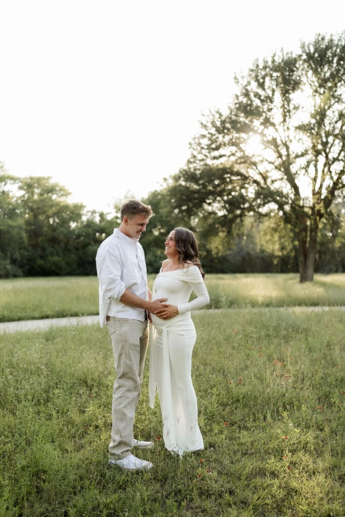 Couple posing in the grassy field during their golden hour Airfield Falls Maternity session