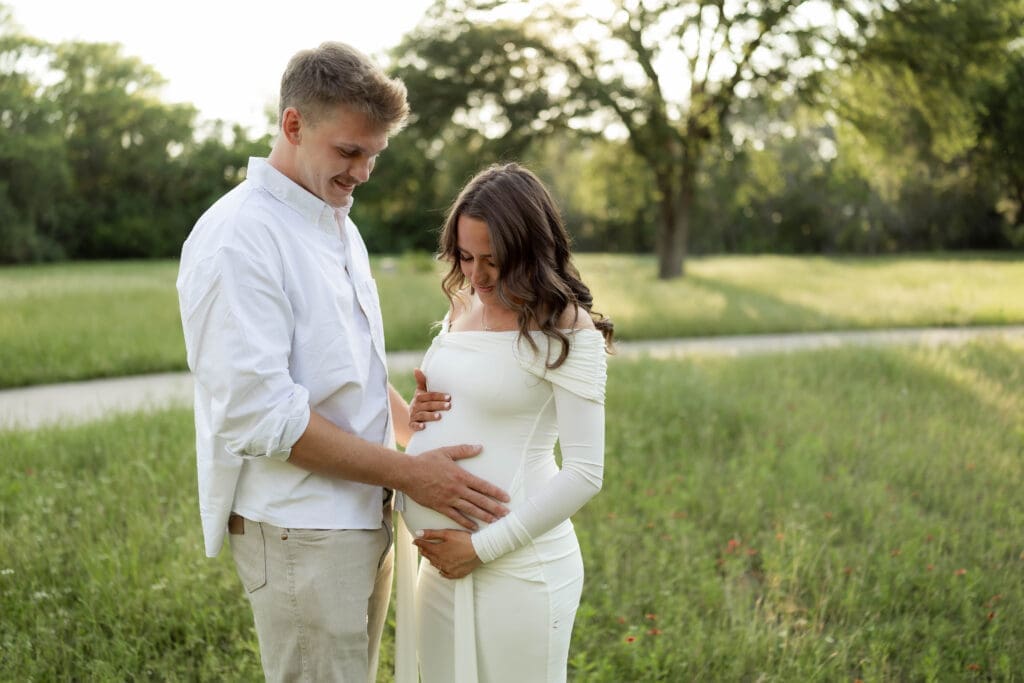Couple posing in the grassy field during their golden hour Airfield Falls Maternity session