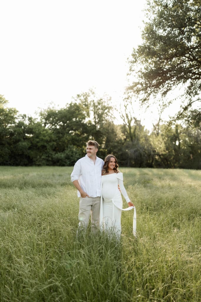 Couple posing in the grassy field during their golden hour Airfield Falls Maternity session
