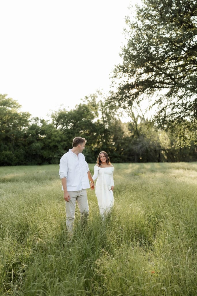 Couple posing in the grassy field during their golden hour Airfield Falls Maternity session
