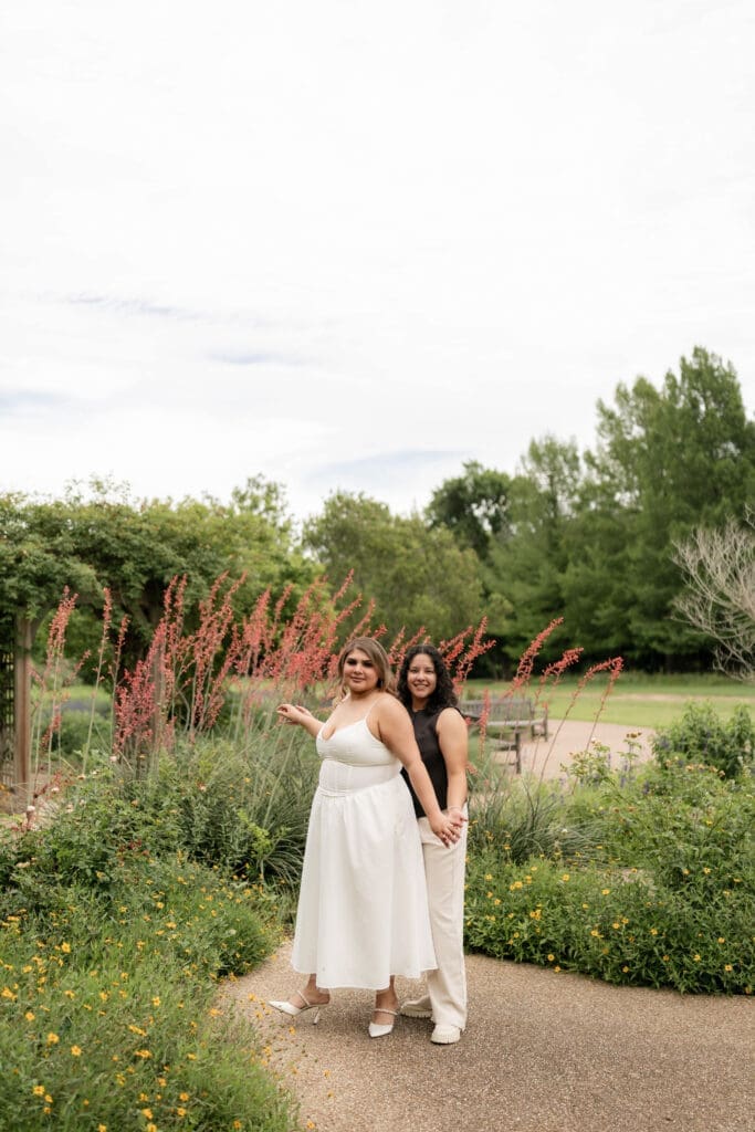 Two women holding hands in the garden during their Fort Worth engagement session at the Fort Worth Botanic Garden