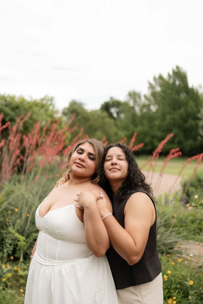 Two women holding hands in the garden during their Fort Worth engagement session at the Fort Worth Botanic Garden