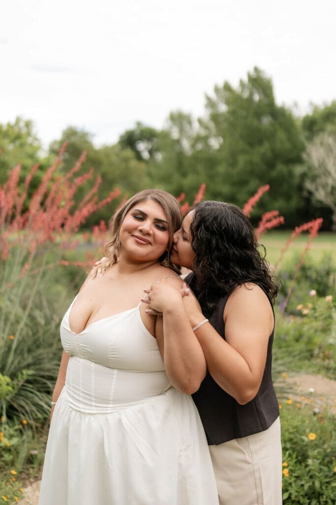Two women kissing in the garden during their Fort Worth engagement session at the Fort Worth Botanic Garden