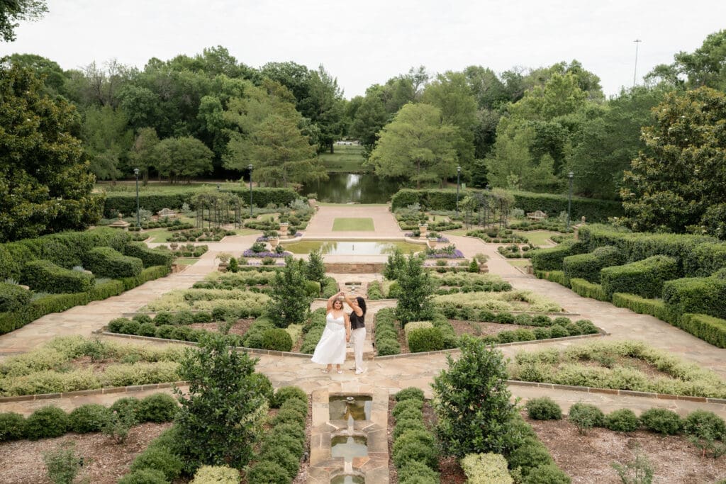 Two women dancing in the courtyard during their Fort Worth engagement session at the Fort Worth Botanic Garden