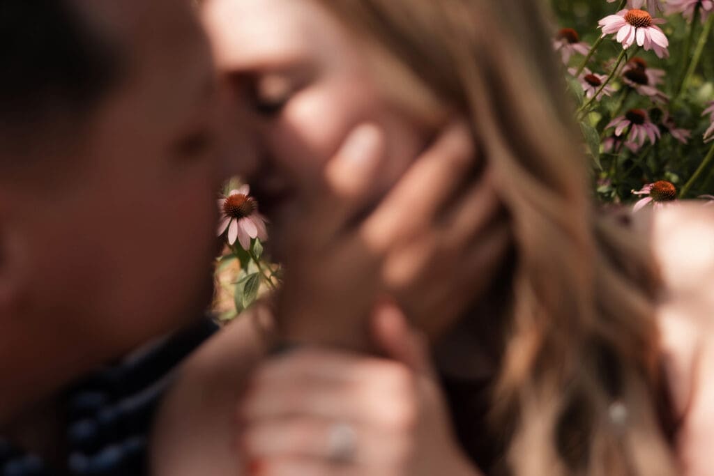 Man and woman kissing amongst the flowers in the Fort Worth Botanic Garden during their proposal engagement session in Fort Worth, TX