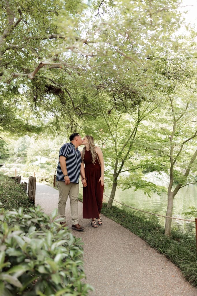 Man and woman walking, holding hands in the Japanese Gardens during their engagement photos at the Fort Worth Botanic Garden in Fort Worth, TX