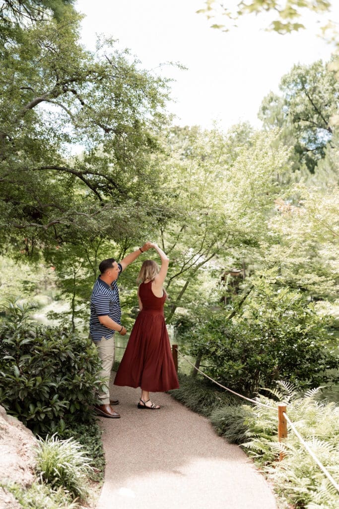 Man and woman walking, holding hands in the Japanese Gardens during their engagement photos at the Fort Worth Botanic Garden in Fort Worth, TX