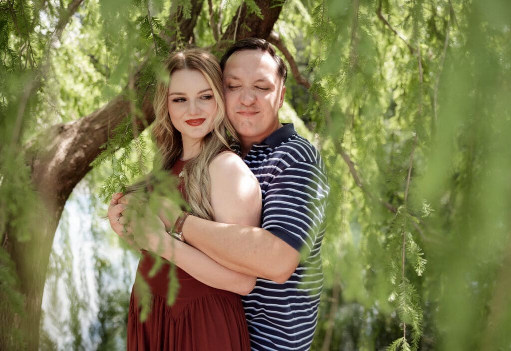 Man and woman cuddling in the Fort Worth Botanic Garden during their proposal engagement session in Fort Worth, TX