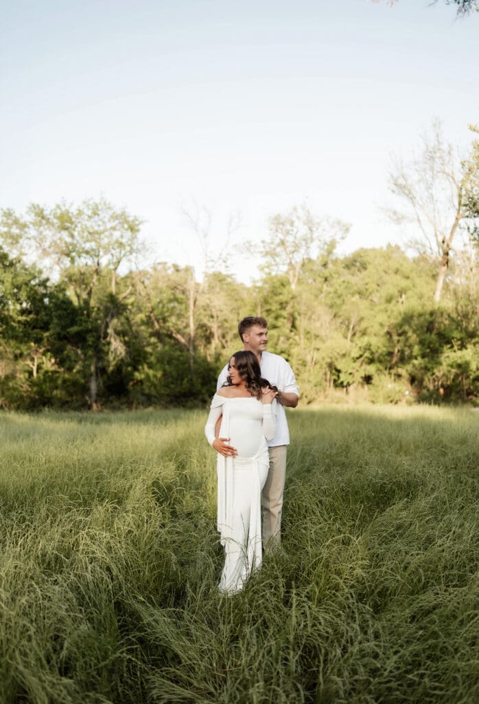 Couple posing in the grassy field during their golden hour Airfield Falls Maternity session