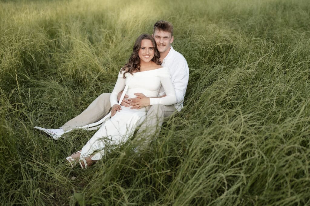 Couple posing in the grassy field during their golden hour Airfield Falls Maternity session