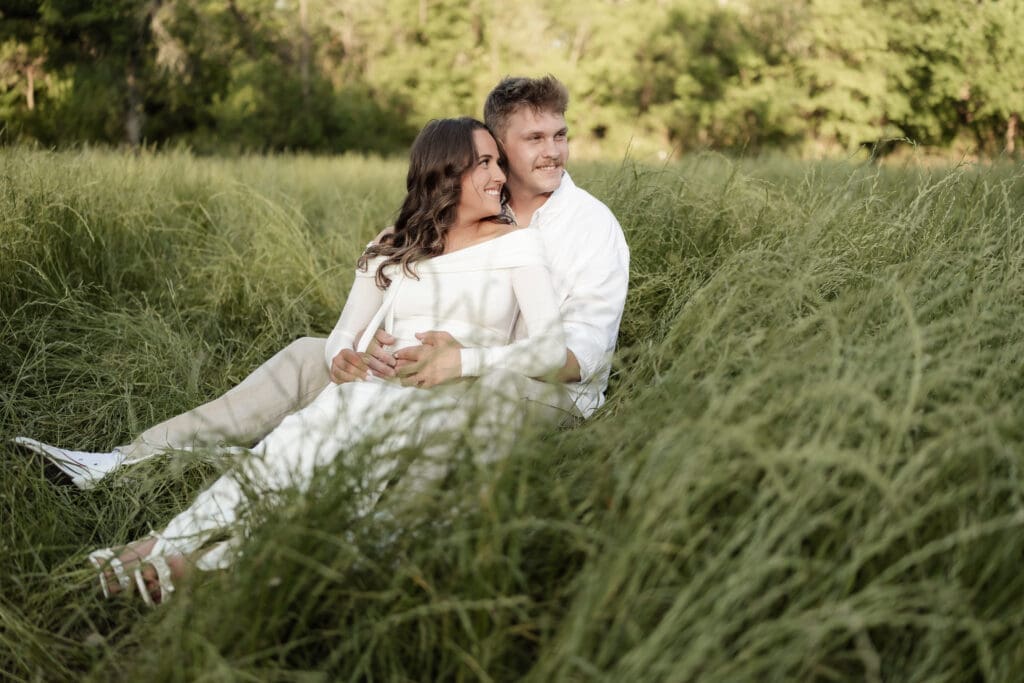 Couple laughing in the grassy field during their golden hour Airfield Falls Maternity session
