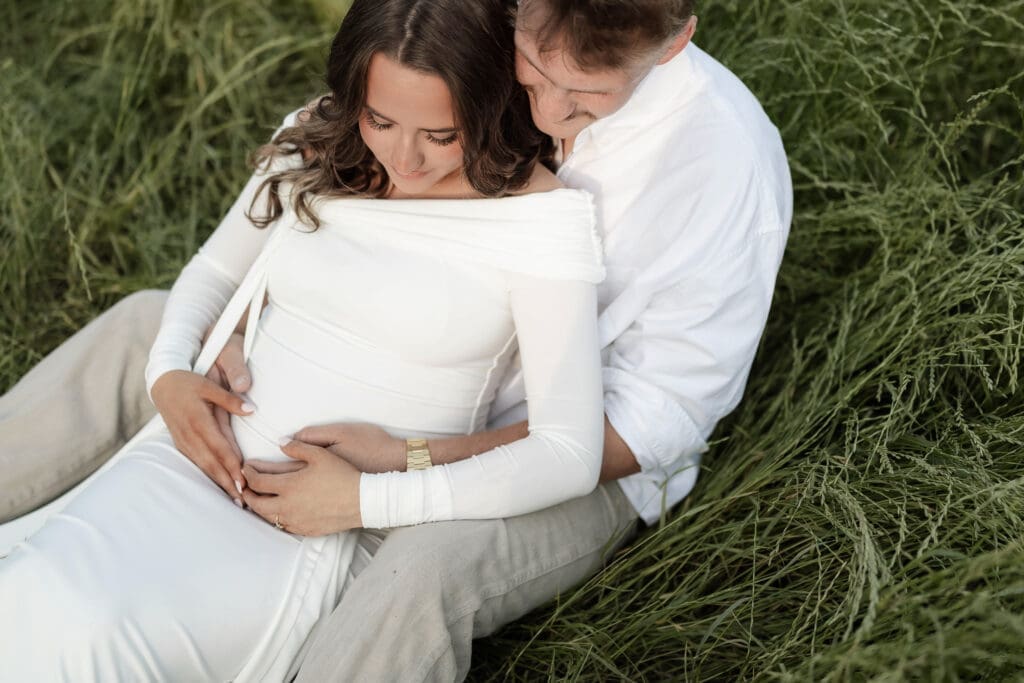 Couple laughing in the grassy field during their golden hour Airfield Falls Maternity session