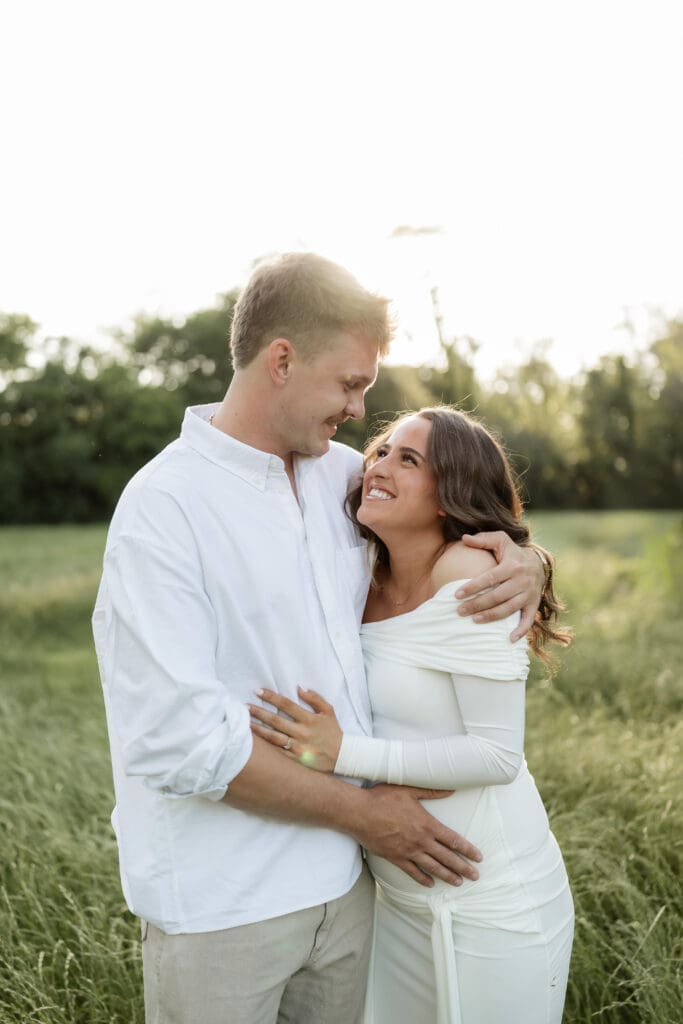 Couple laughing in the grassy field during their golden hour Airfield Falls Maternity session