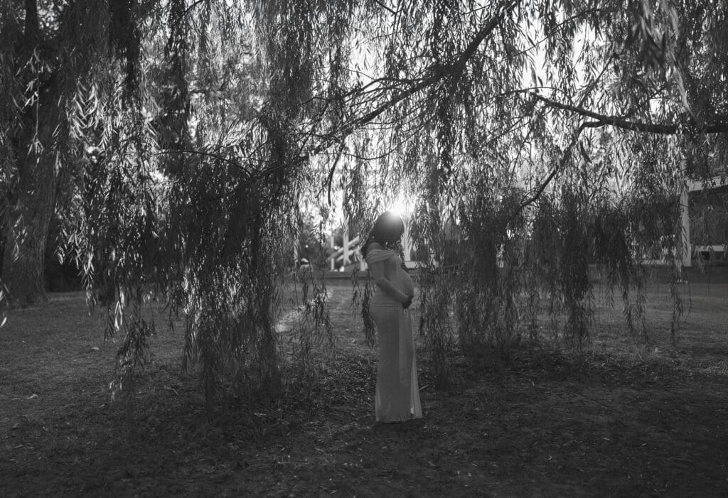 Black and white Silhouette of a woman posing for her maternity session at Airfield Falls in Fort Worth, TX