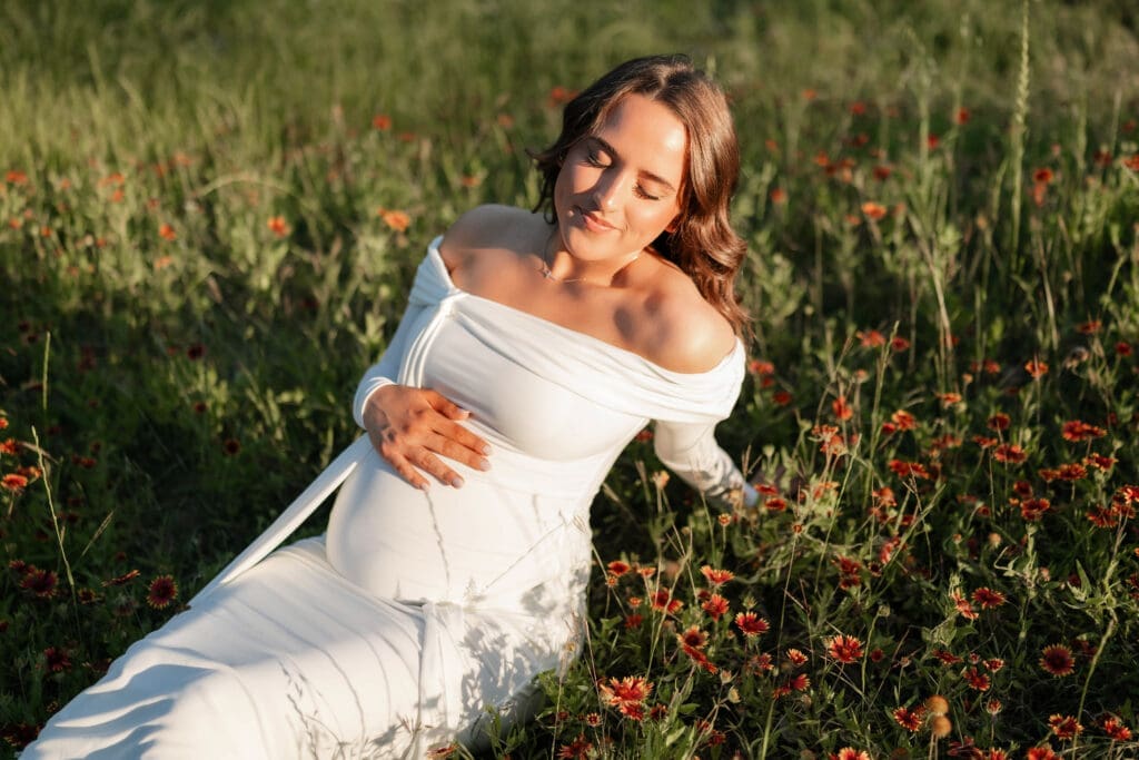Woman laying in wildflowers during her golden hour Airfield Falls Maternity session