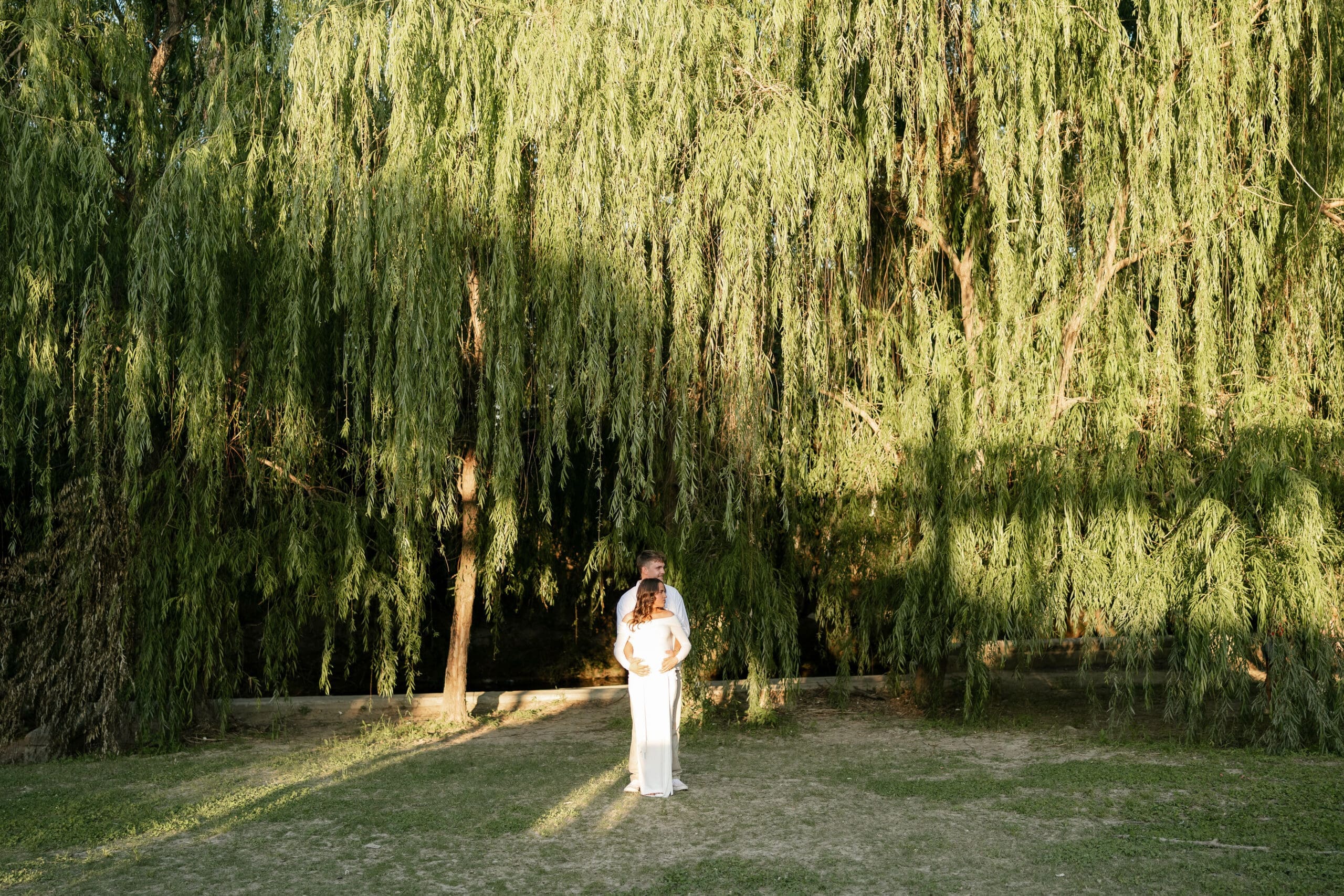 Couple posing in front of the willow tree at Airfield Falls Park during their maternity session