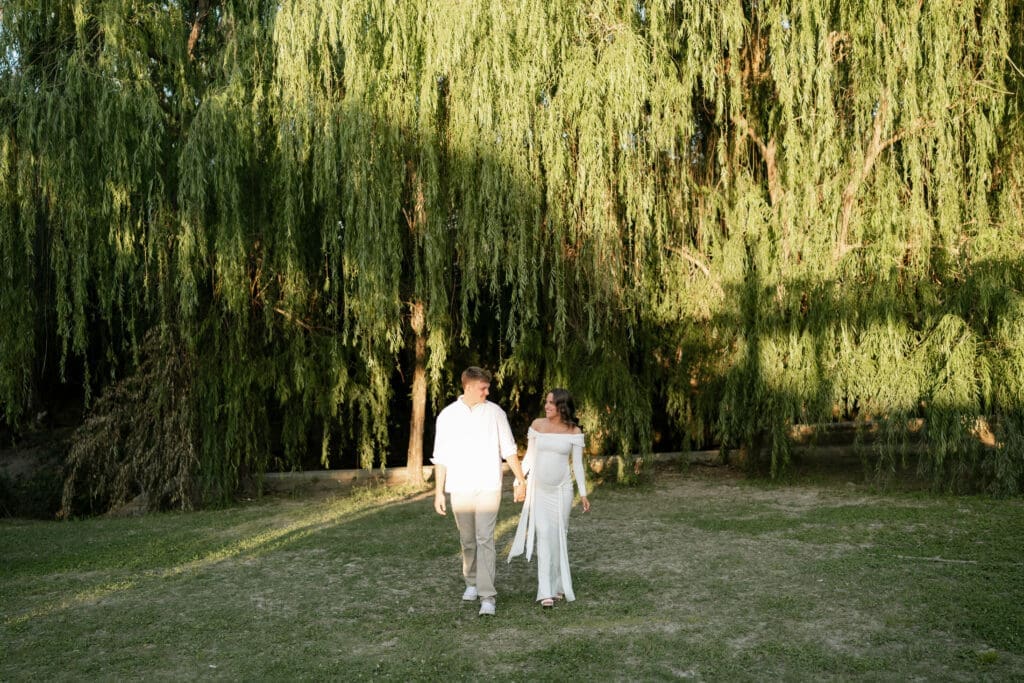 Couple posing in front of the willow tree during their golden hour Airfield Falls Maternity session