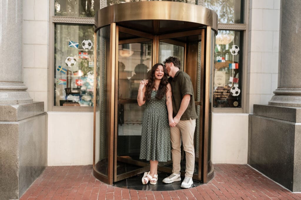 Man and woman embracing in a doorway in Sundance Square, Fort Worth, TX during their engagement photo session