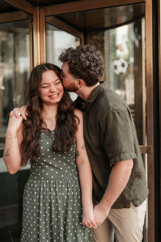Man and woman embracing in a doorway in Sundance Square, Fort Worth, TX during their engagement photo session