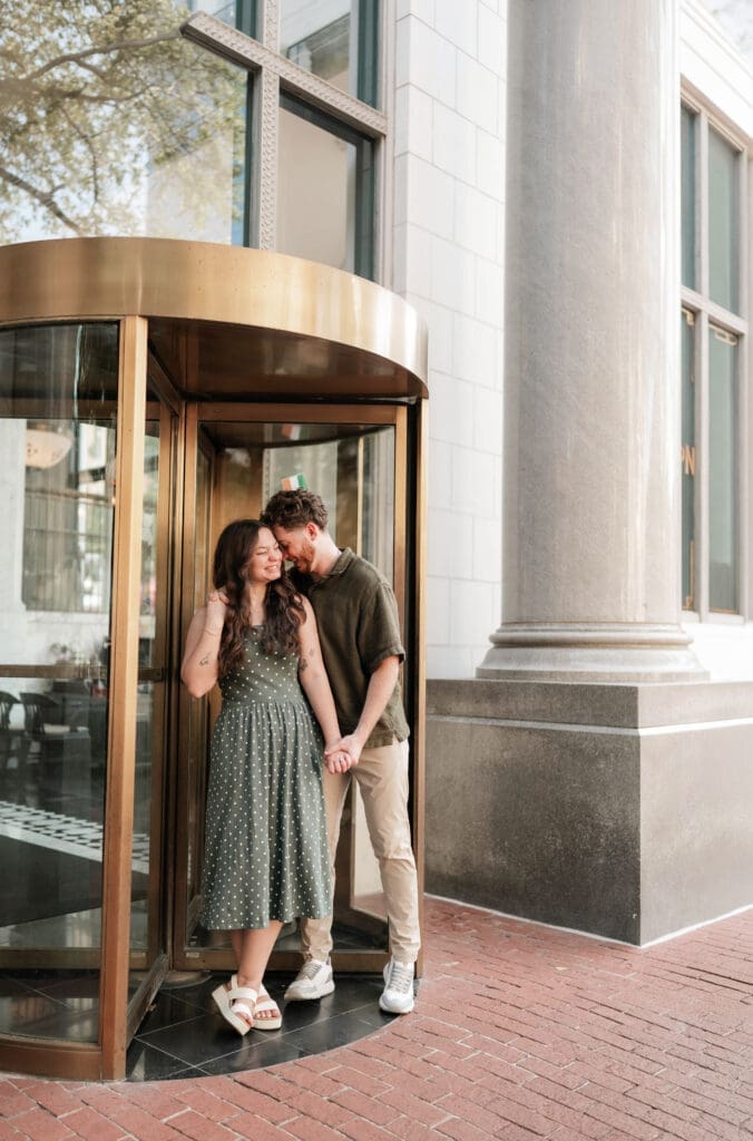 Man and woman embracing in a doorway in Sundance Square, Fort Worth, TX during their engagement photo session