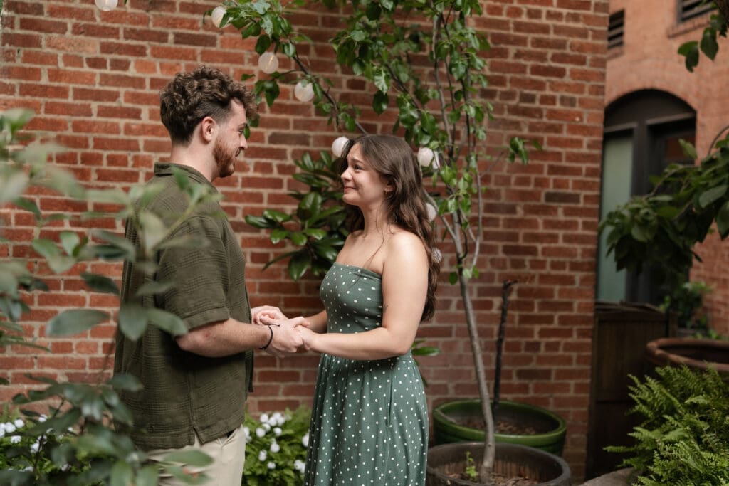 Man and woman holding hands in Sundance Alley during their engagement photo session in Fort Worth, TX
