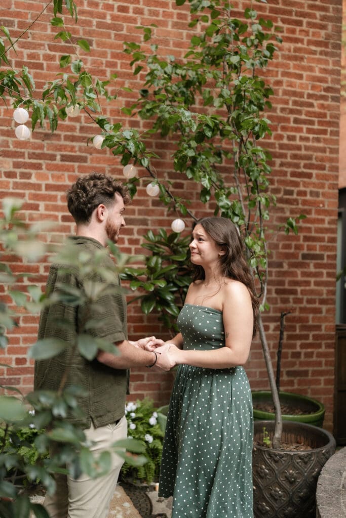 Man and woman holding hands in Sundance Alley during their engagement photo session in Fort Worth, TX