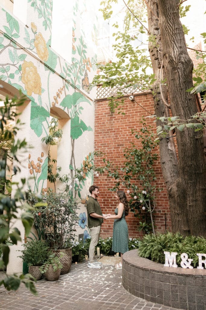 Man and woman holding hands in Sundance Alley during their engagement photo session in Fort Worth, TX