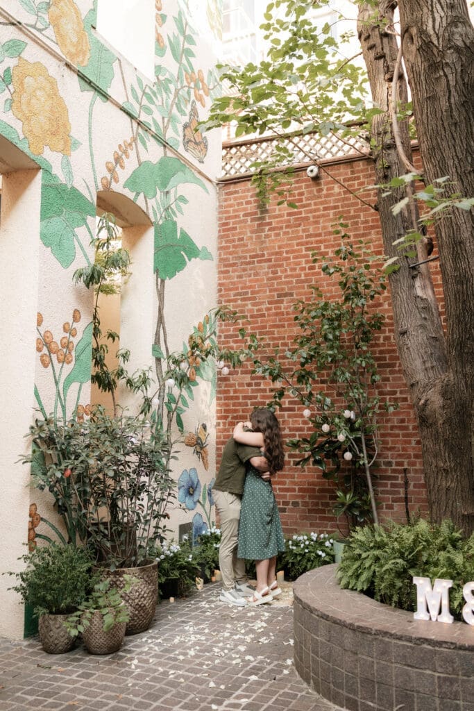 Man and woman embracing and kissing after he proposed to her in Sundance Alley in Sundance Square, Fort Worth, TX