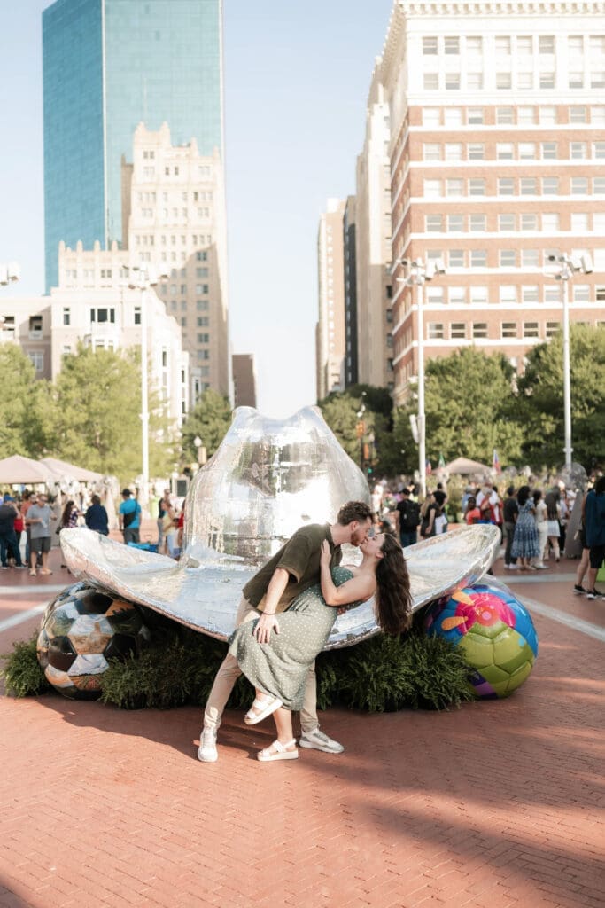 Man and woman dip kissing in front of the disco hat in Sundance Square