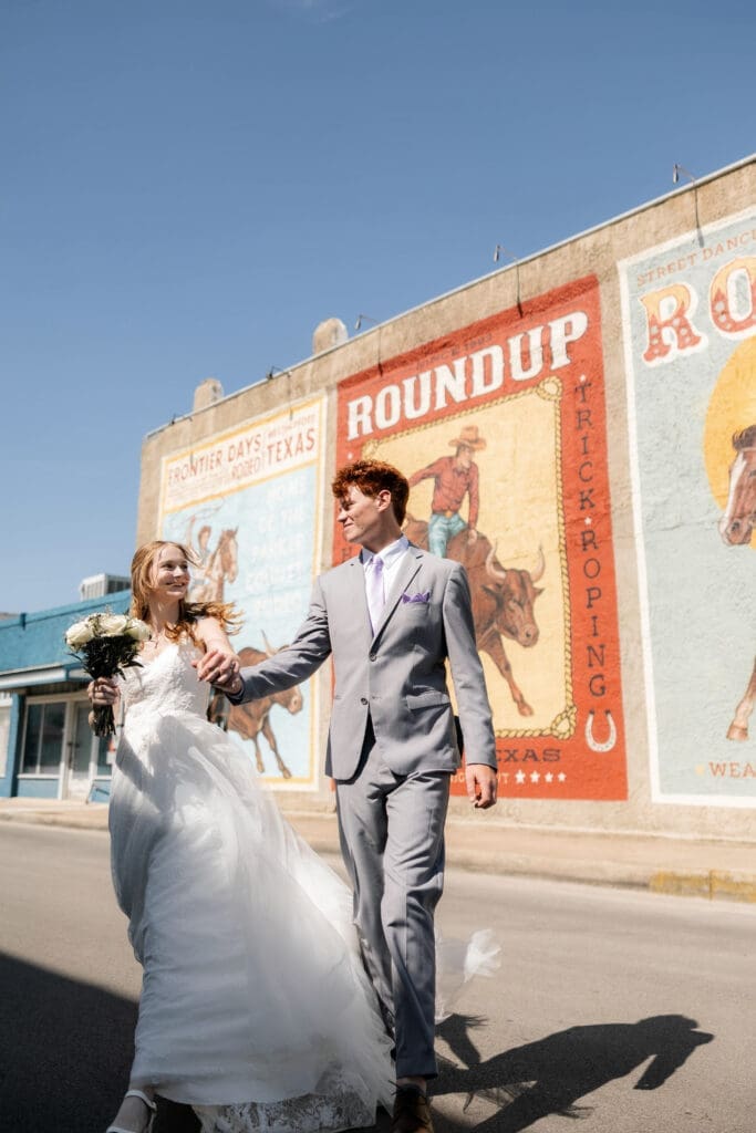 Bride and groom running across the street in downtown Weatherford, TX 