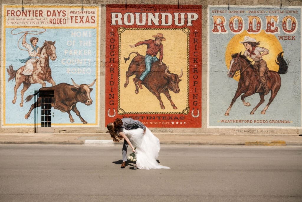 Bride and groom kissing in front of large mural in downtown Weatherford, TX