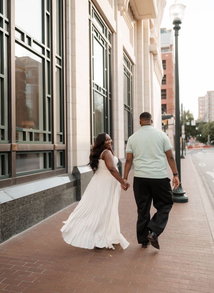 Couple walking outside of Bass Hall during their golden hour engagement session in Fort Worth, TX