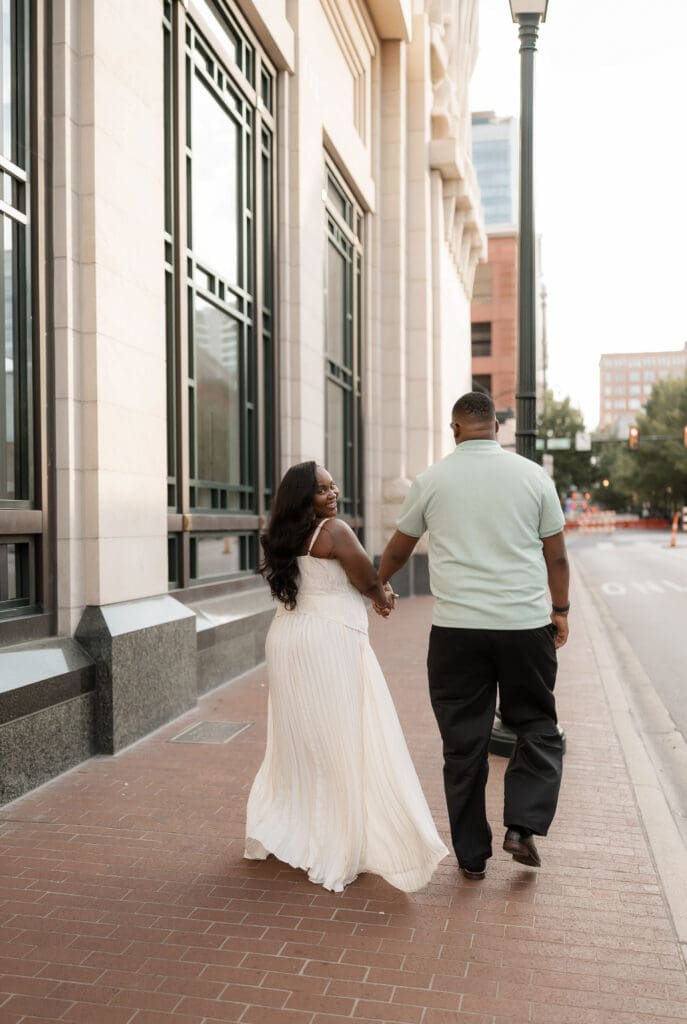 Couple walking outside of Bass Hall during their golden hour engagement session in Fort Worth, TX
