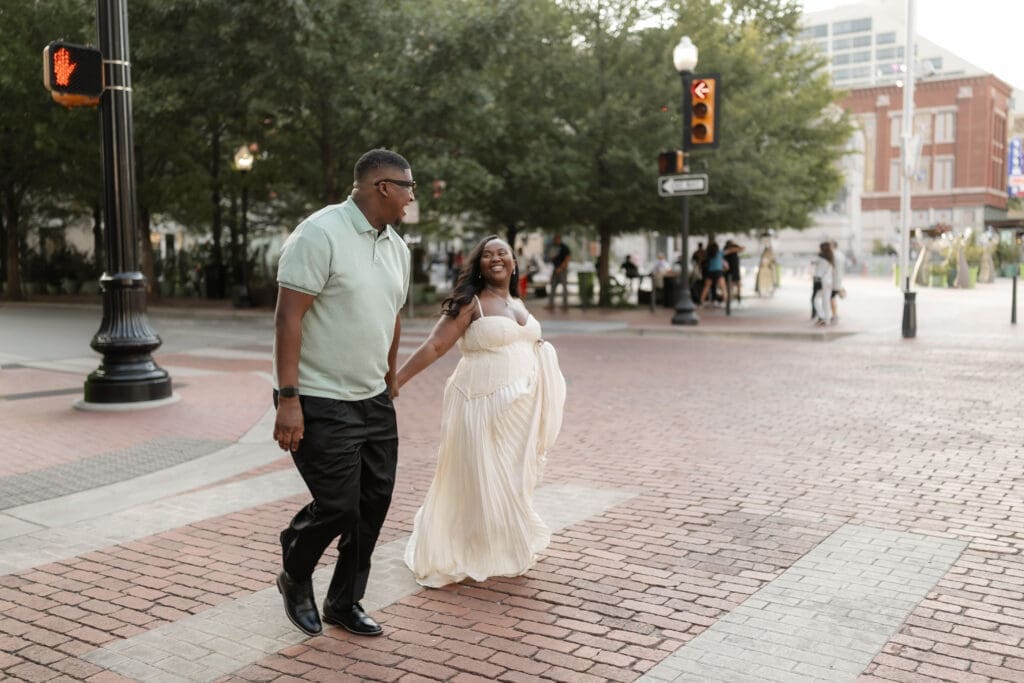 Couple running across the crosswalk during their golden hour engagement session in Fort Worth, TX