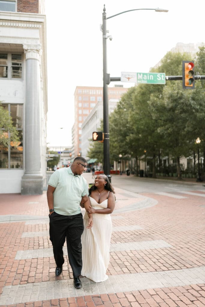 Couple running across the crosswalk during their golden hour engagement session in Fort Worth, TX