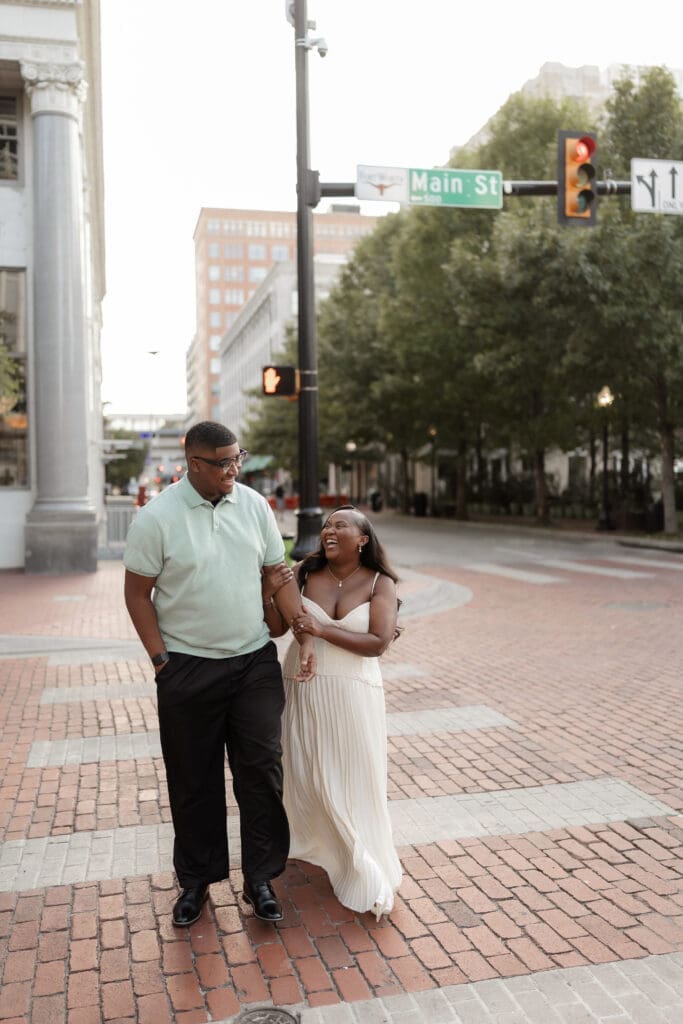 Couple running across the crosswalk during their golden hour engagement session in Fort Worth, TX