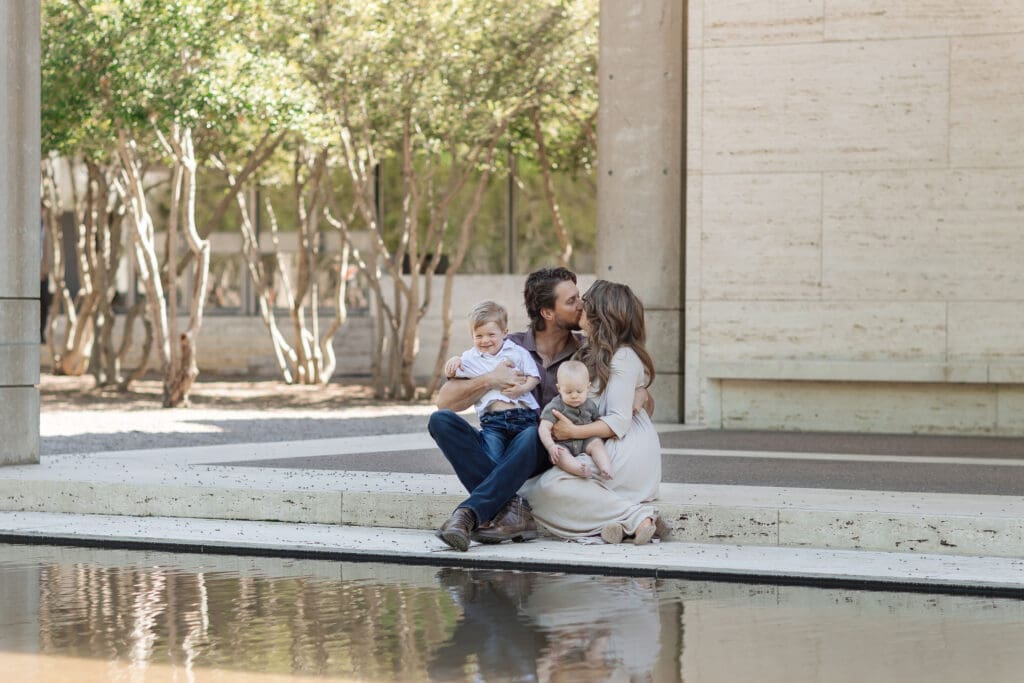 Family snuggling on the steps at Kimbell Art Museum during their family portrait session in Fort Worth