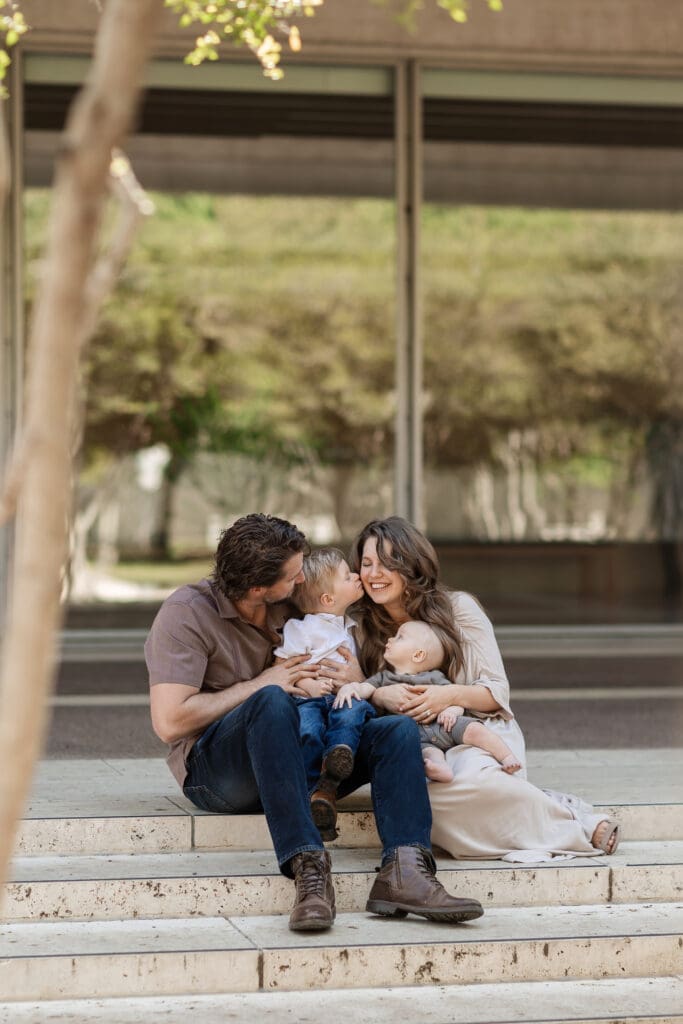 Family snuggling on the steps at Kimbell Art Museum during their family portrait session in Fort Worth