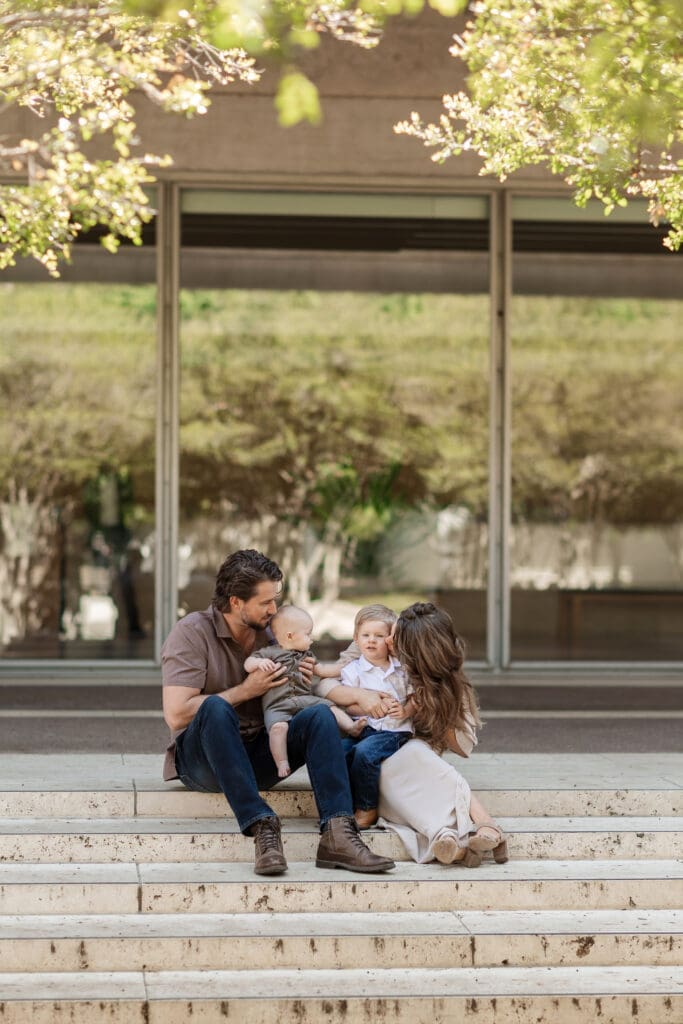 Family snuggling on the steps at Kimbell Art Museum during their family portrait session in Fort Worth