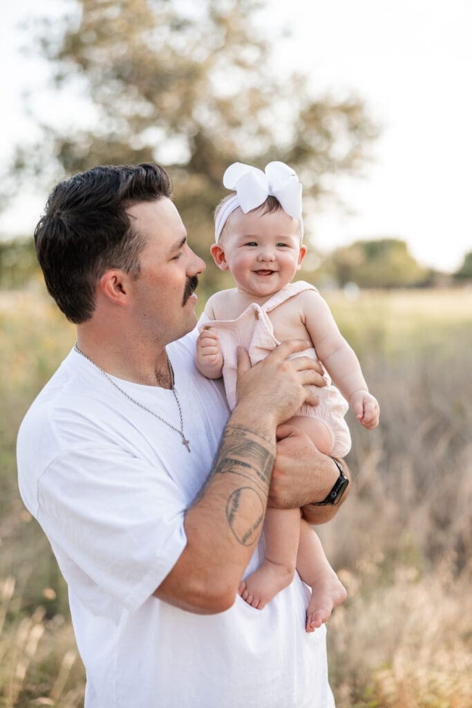 Dad holding his baby standing in the field at Tandy Hills in Fort Worth for a family photography session