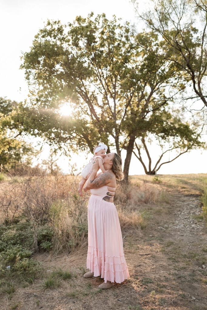 Mom holding her baby standing in the field at Tandy Hills in Fort Worth for a family photography session