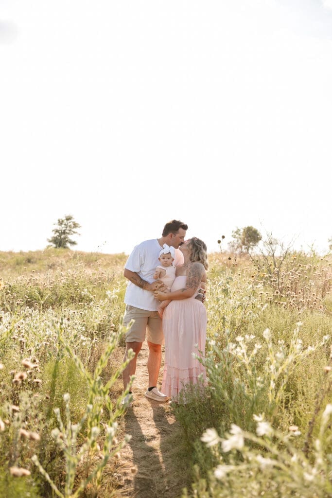 Husband and wife holding their baby standing in the field at Tandy Hills in Fort Worth for their family photography session