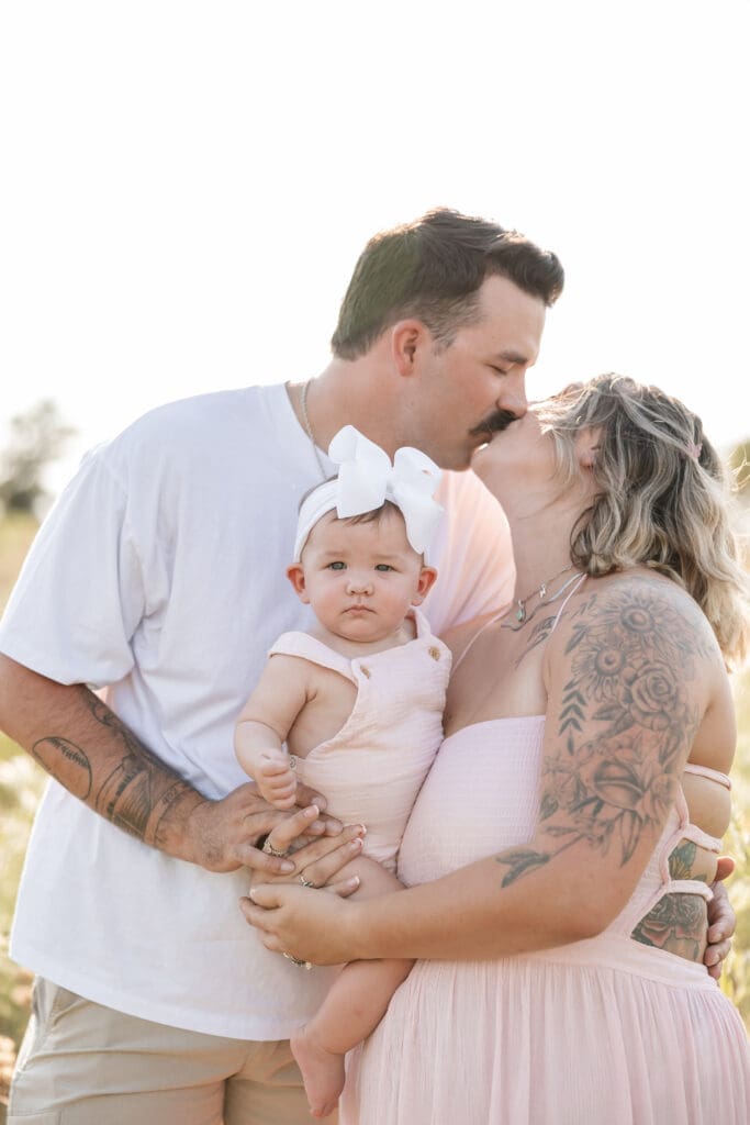 Husband and wife holding their baby standing in the field at Tandy Hills in Fort Worth for their family photography session