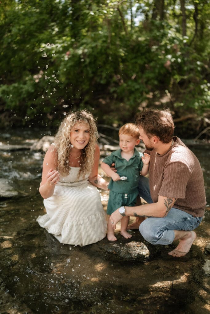 Husband and wife with their toddler standing in the creek at Ikard Trail in Weatherford for family photos