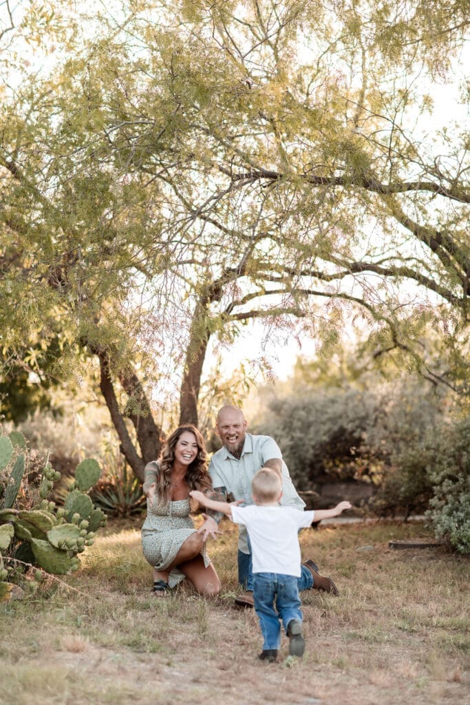 Husband and wife holding their arms out towards their toddler at the Cactus Garden in Fort Worth during their family photography session
