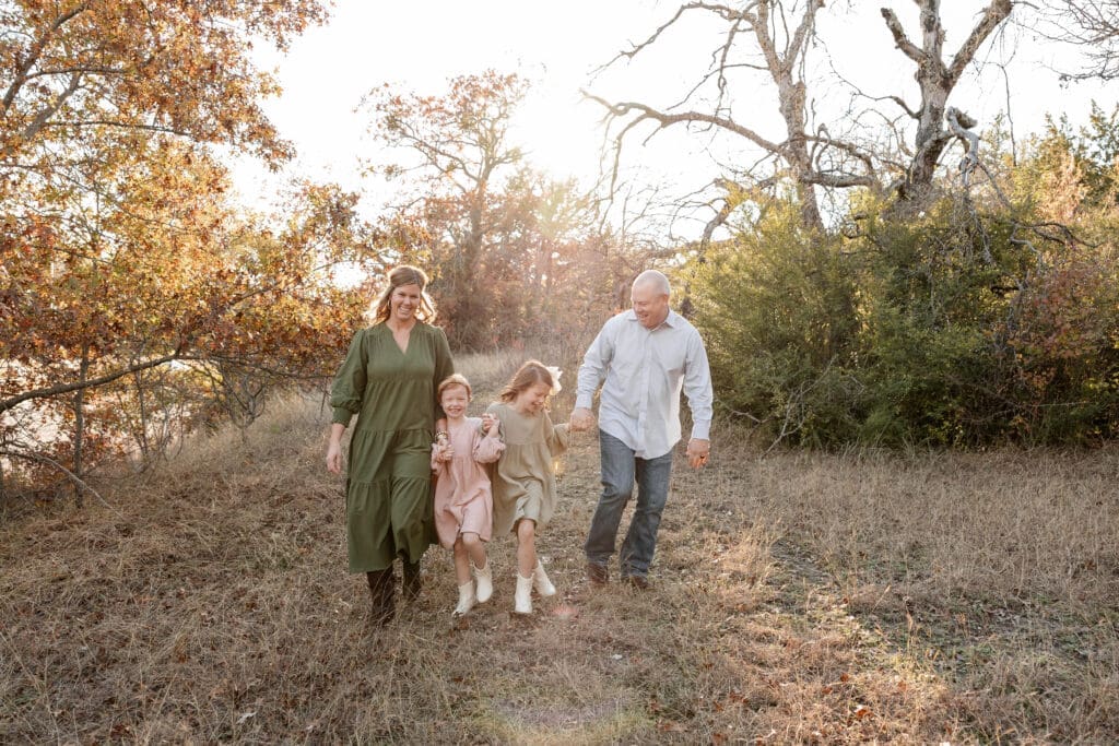 Family skipping in grass during their family photos at Soldier Spring Park in Weatherford