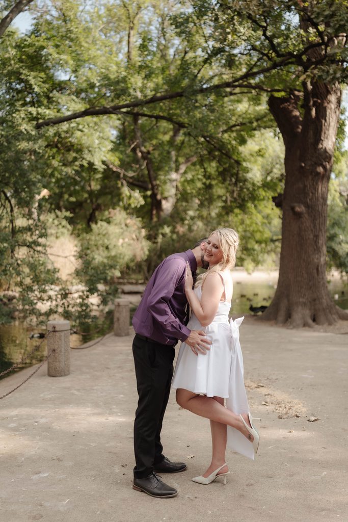 Bride and groom taking wedding portraits in front of the duck pond at Trinity Park in Fort Worth, TX